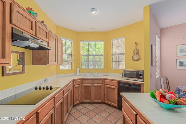 kitchen featuring tile counters, light tile patterned floors, black appliances, and sink