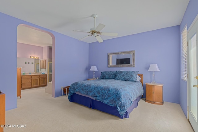 bedroom featuring ceiling fan, light colored carpet, and ensuite bath