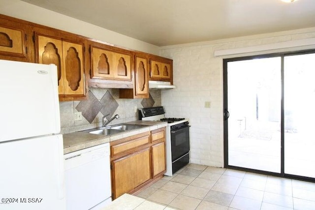 kitchen with decorative backsplash, light tile patterned flooring, white appliances, and sink