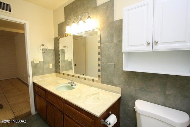 bathroom featuring tile patterned flooring, vanity, tile walls, and toilet