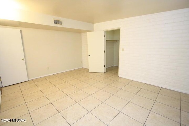 interior space with light tile patterned flooring, a closet, and brick wall