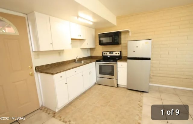 kitchen with electric stove, white cabinets, white fridge, and brick wall