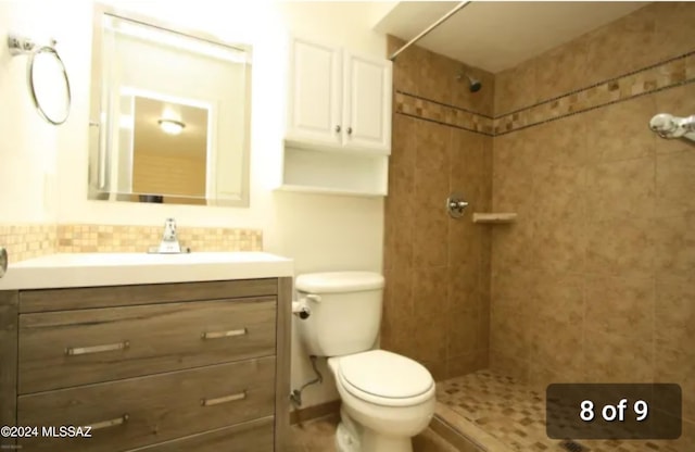 bathroom with a tile shower, vanity, and toilet