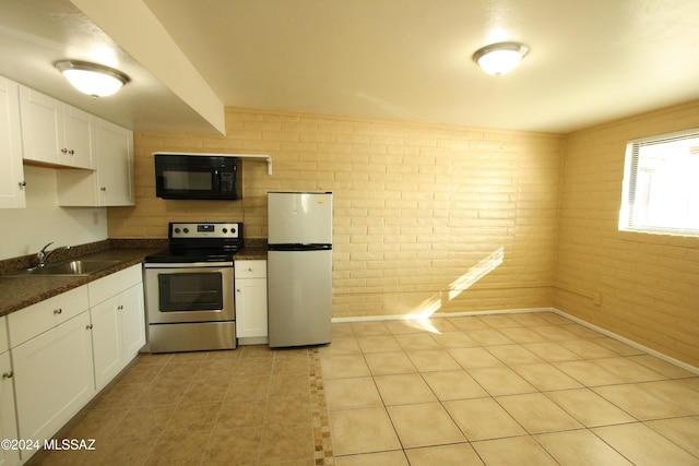 kitchen with refrigerator, brick wall, sink, white cabinets, and stainless steel electric range