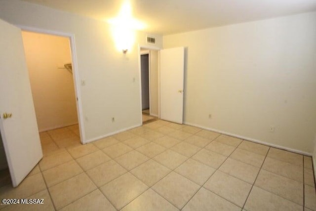 unfurnished bedroom featuring a walk in closet, a closet, and light tile patterned floors