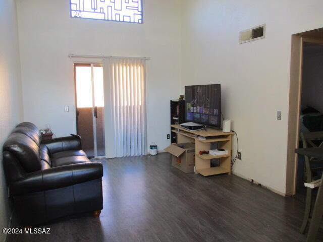 living room featuring a towering ceiling and dark wood-type flooring