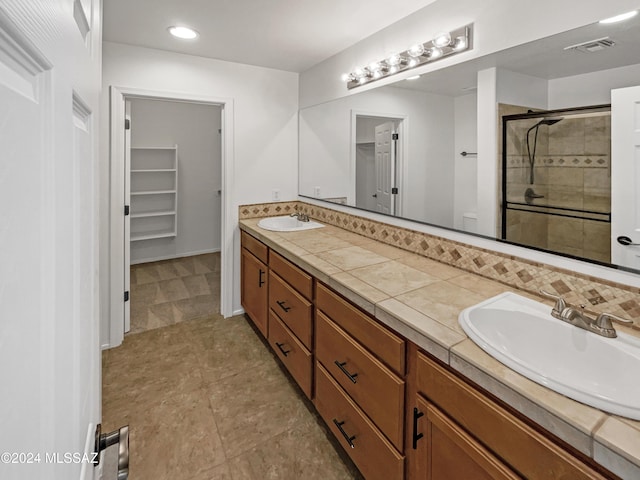 bathroom with tile patterned floors, decorative backsplash, vanity, and tiled shower