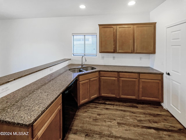 kitchen featuring kitchen peninsula, sink, dark stone countertops, black dishwasher, and dark hardwood / wood-style floors