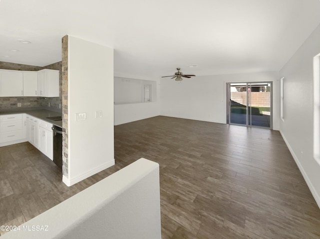 unfurnished living room with ceiling fan, sink, and dark wood-type flooring