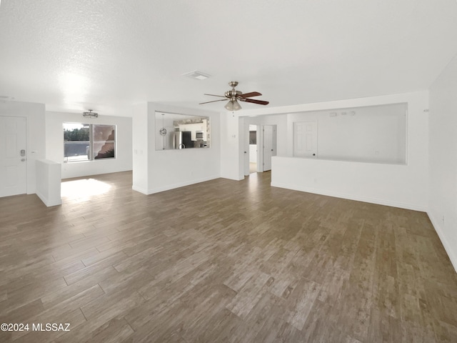 unfurnished living room featuring ceiling fan, dark wood-type flooring, and a textured ceiling