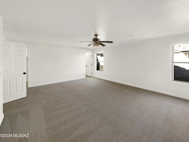 carpeted spare room featuring a wealth of natural light and ceiling fan