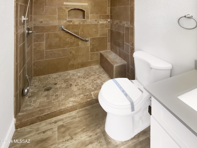 bathroom with vanity, toilet, and a tile shower