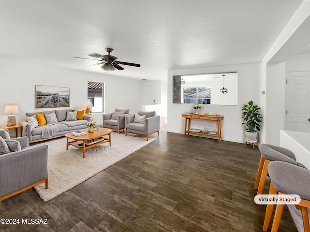 living room with a textured ceiling, dark hardwood / wood-style flooring, and ceiling fan