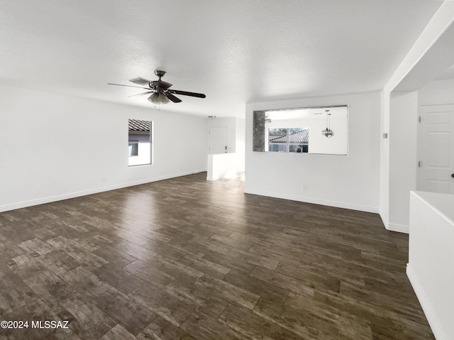 unfurnished living room with ceiling fan, dark hardwood / wood-style flooring, a textured ceiling, and a wealth of natural light