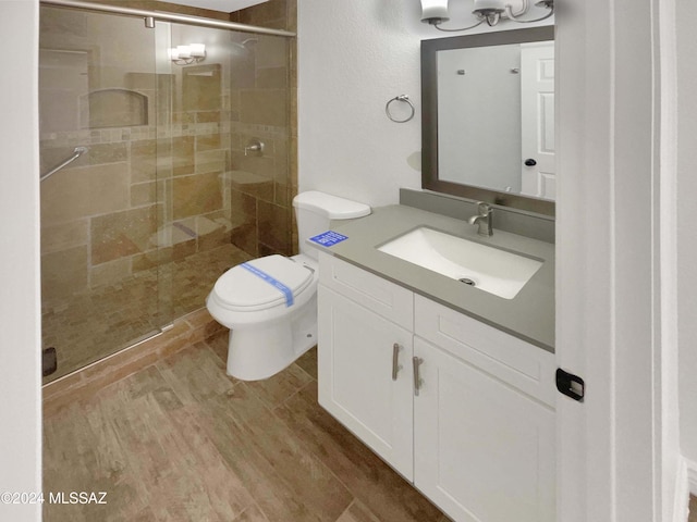 bathroom with vanity, hardwood / wood-style flooring, toilet, and a shower with shower door