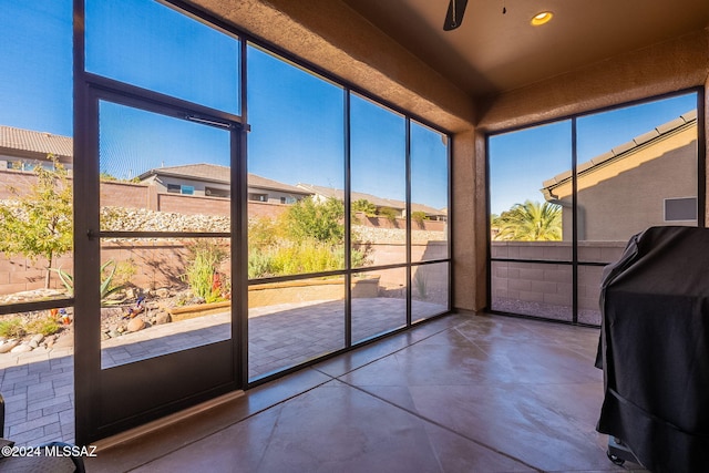 unfurnished sunroom with ceiling fan