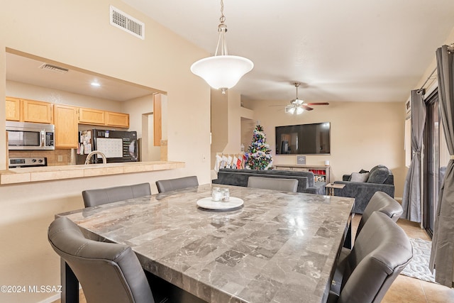 dining room featuring ceiling fan, lofted ceiling, and light tile patterned floors