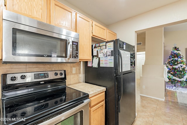 kitchen featuring tile countertops, light brown cabinets, stainless steel appliances, and tasteful backsplash