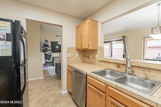 kitchen featuring backsplash, black refrigerator, sink, stainless steel dishwasher, and decorative light fixtures