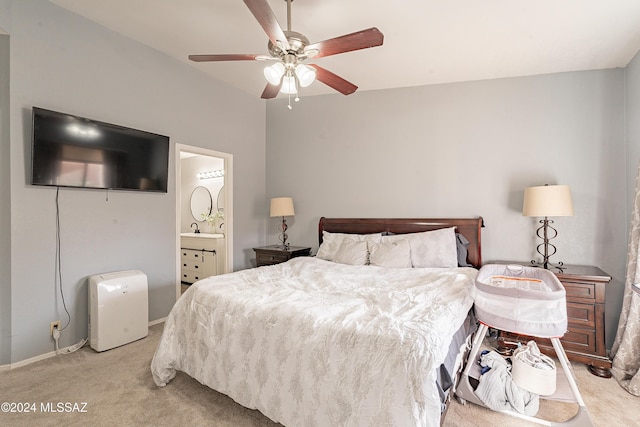 bedroom with connected bathroom, light colored carpet, and ceiling fan