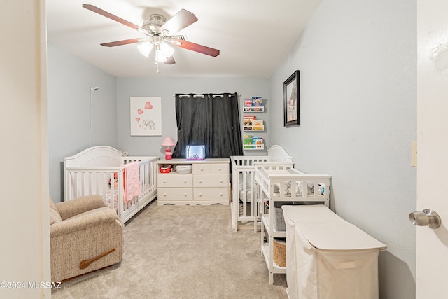 bedroom featuring carpet, ceiling fan, and a nursery area