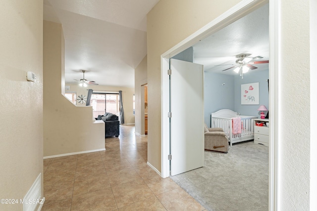 corridor featuring light tile patterned floors and vaulted ceiling