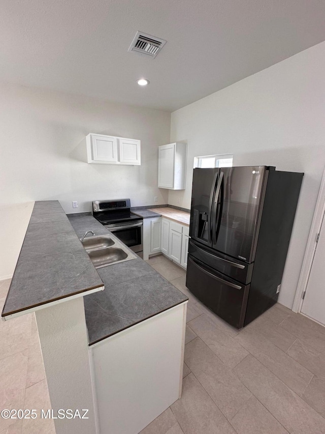 kitchen with stainless steel electric stove, white cabinets, fridge with ice dispenser, and sink