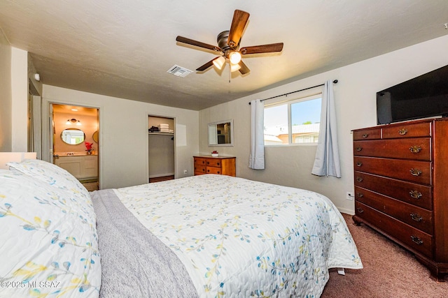 carpeted bedroom with ensuite bathroom and ceiling fan