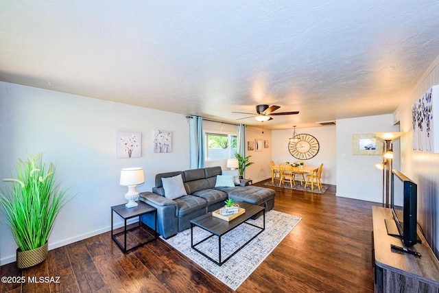 living room featuring ceiling fan, dark wood-type flooring, and a textured ceiling