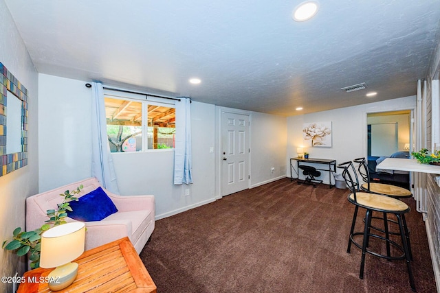 sitting room featuring dark colored carpet and a textured ceiling