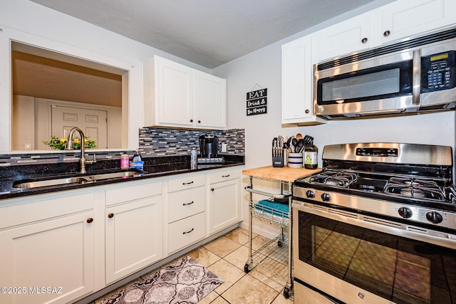 kitchen featuring light tile patterned flooring, stainless steel appliances, white cabinetry, and sink