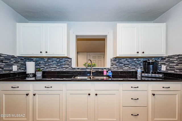 kitchen with dark stone countertops, sink, and white cabinets