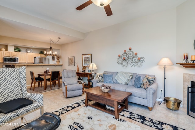 living room with a tile fireplace, ceiling fan with notable chandelier, and light tile patterned floors