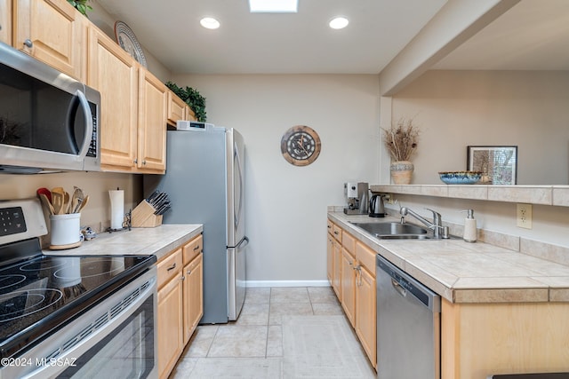 kitchen featuring appliances with stainless steel finishes, sink, tile countertops, and light brown cabinets