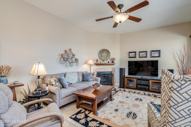 tiled living room with a tile fireplace and ceiling fan