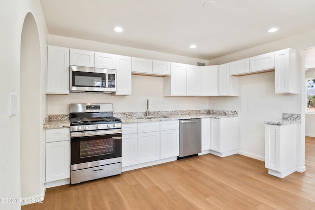 kitchen with white cabinets, sink, appliances with stainless steel finishes, and light hardwood / wood-style flooring