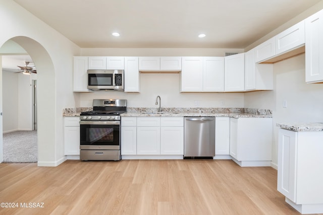 kitchen featuring sink, white cabinets, stainless steel appliances, and light wood-type flooring