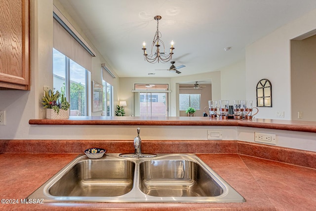 kitchen featuring ceiling fan with notable chandelier, decorative light fixtures, sink, and a wealth of natural light