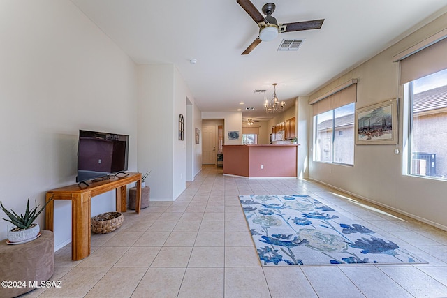 tiled living room with ceiling fan with notable chandelier