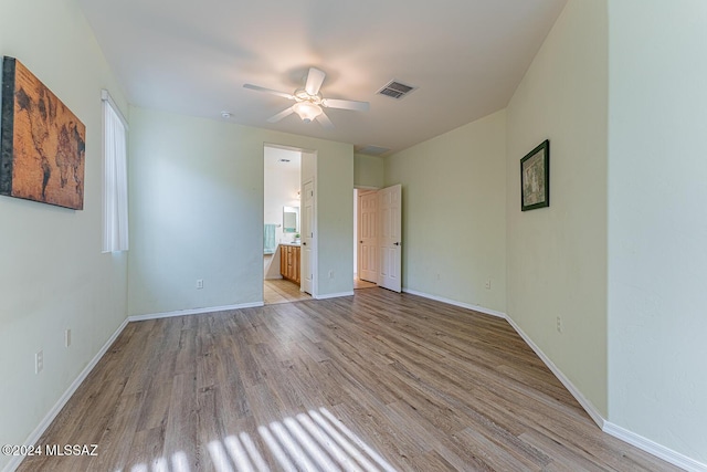 unfurnished bedroom featuring ensuite bath, ceiling fan, and light wood-type flooring