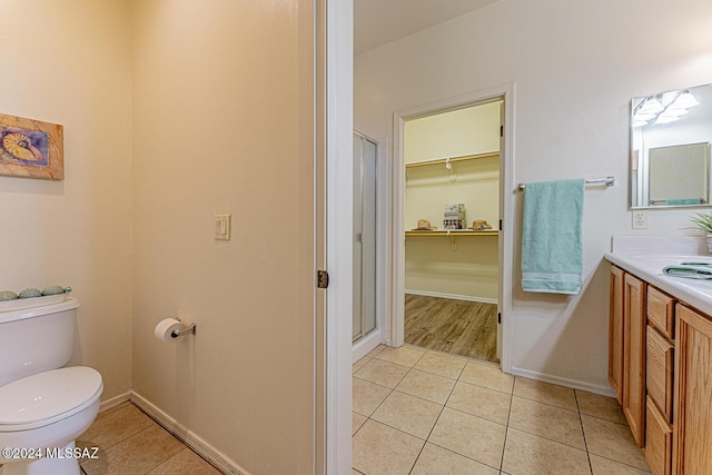 bathroom with tile patterned floors, vanity, a shower with shower door, and toilet