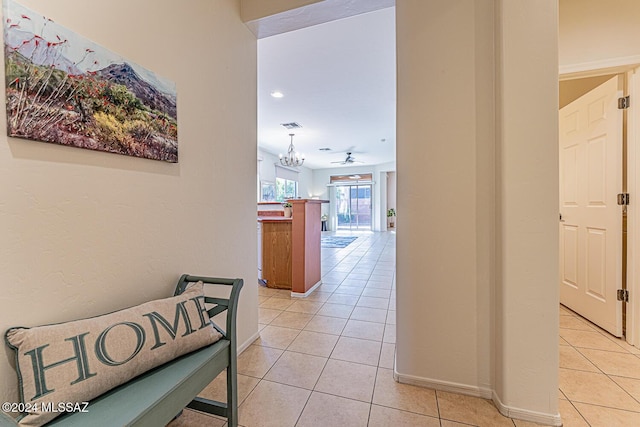 hallway featuring light tile patterned flooring and an inviting chandelier