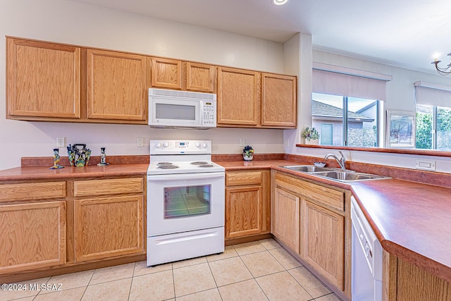 kitchen with white appliances, sink, light tile patterned floors, and an inviting chandelier