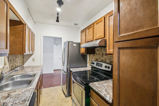 kitchen with light stone countertops, appliances with stainless steel finishes, decorative backsplash, and sink