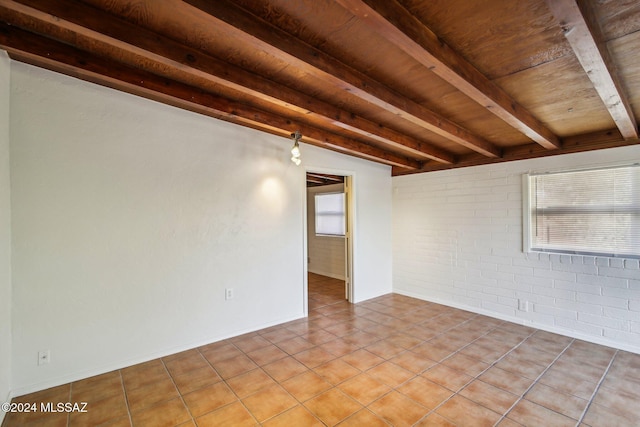 tiled spare room featuring beam ceiling, wood ceiling, and brick wall