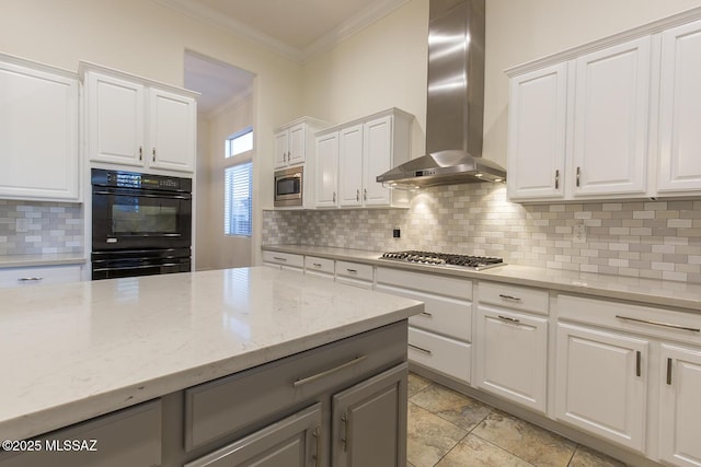 kitchen with appliances with stainless steel finishes, white cabinetry, and wall chimney exhaust hood