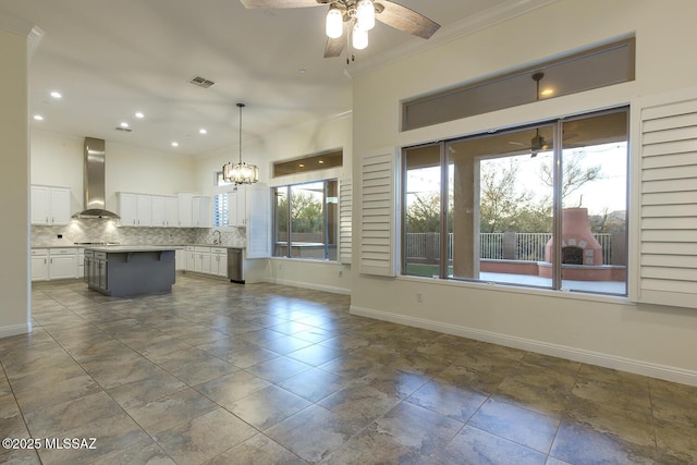 kitchen with backsplash, wall chimney range hood, white cabinets, a center island, and hanging light fixtures