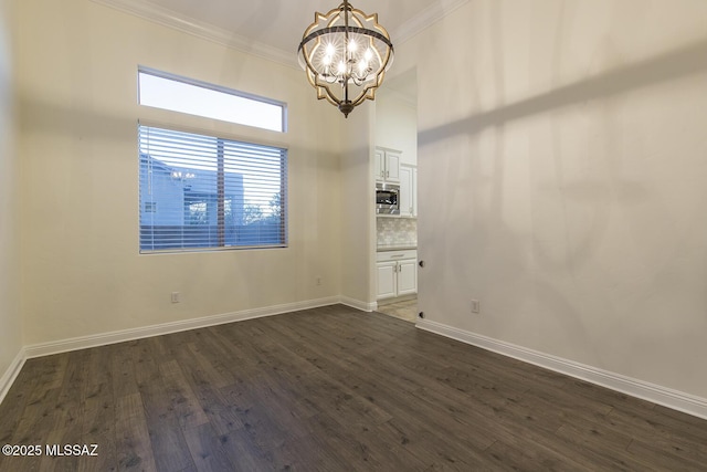 spare room featuring dark hardwood / wood-style floors, ornamental molding, and a chandelier