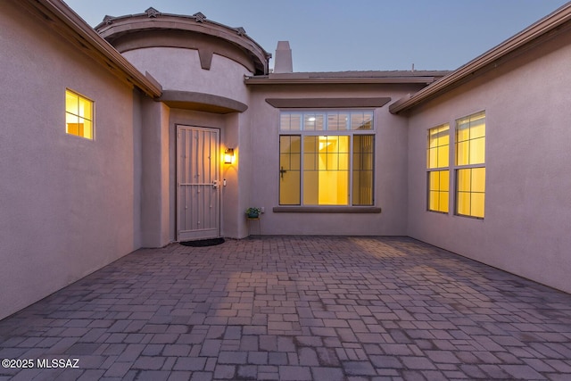 exterior entry at dusk featuring a patio area