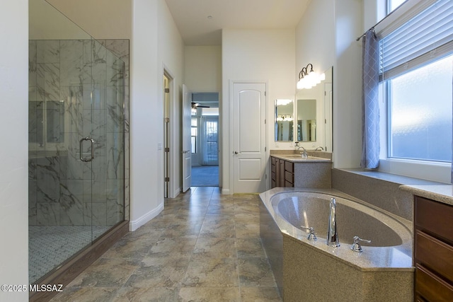 bathroom with plus walk in shower, vanity, ceiling fan, and a healthy amount of sunlight